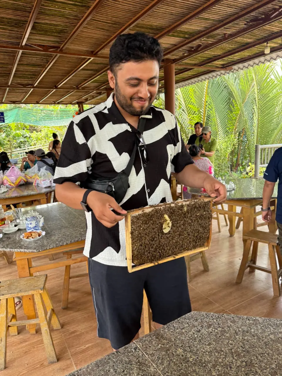 Raghavendra holding up a honeycomb frame covered in bees